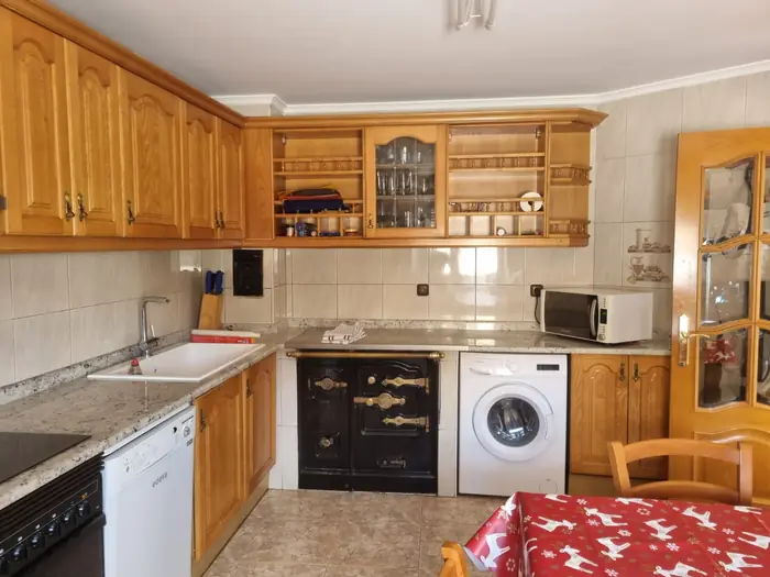 Cocina equipada con cocina económica de leña, lavavajillas y lavadora