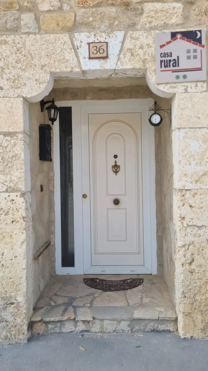 Puerta de entrada de piedra con la placa de casa rural