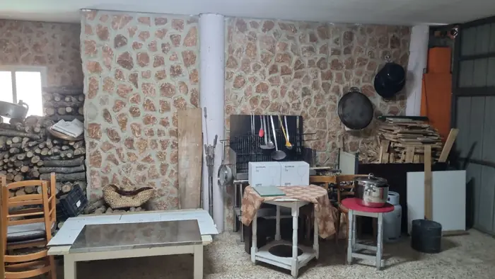 Garaje leñera con parrilla de barbacoa, leña apilada y menaje de cocina